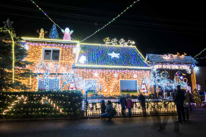 Passanten stehen vor dem weihnachtlich geschmückten Haus von Mario Leicht. Seit zwölf Jahren schmückt Mario Leicht aus dem thüringischen Walschleben jedes Weihnachten sein Familienhaus.