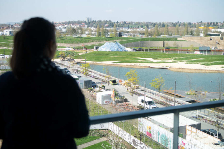 Eine Frau blickt von einem Wohngebäude der Stadtausstellung auf das Gelände der Bundesgartenschau.