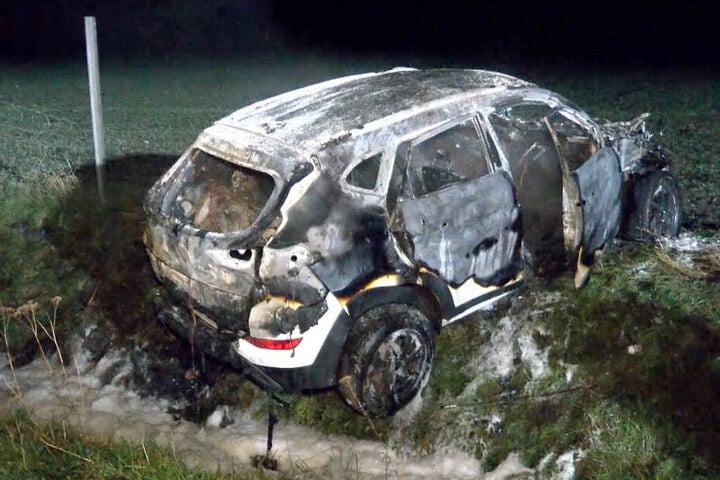 Der SUV steht ausgebrannt auf einer Wiese neben der A1.