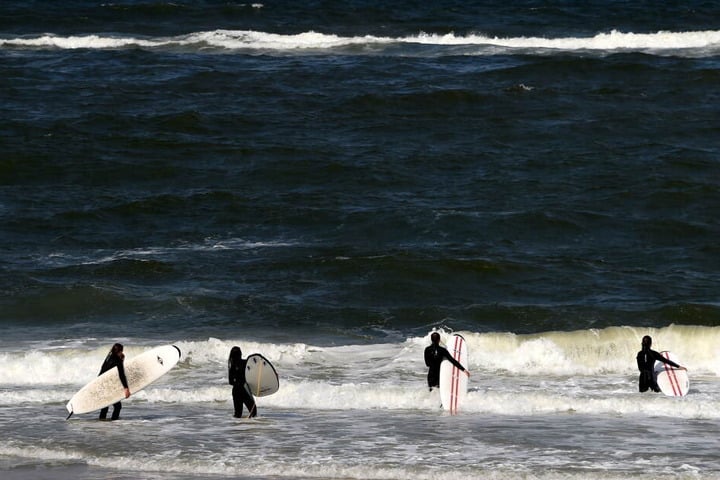Sylt ist ein beliebter Ferienort für Surf-Fans: Hier werfen sich Teilnehmer eines Surf-Kurses am Strand von Westerland auf Sylt (Schleswig-Holstein) in die Wellen. Dank des Windes sind die Strände auf der Nordsee-Insel auch bei Kite-Surfern populär.