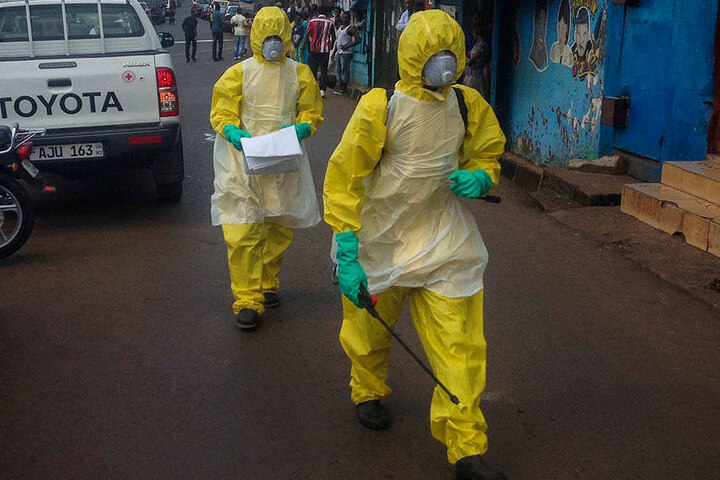 In Schutzanzügen gehen Männer durch eine Straße in Sierra Leone nach einer Ebola-Epidemie.
