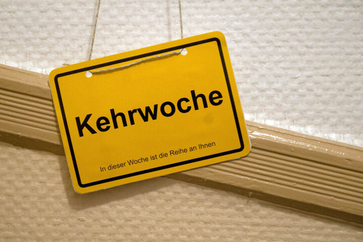 Ein Kehrwoche-Schild hängt an einer Wand in einem Treppenhaus. (Symbolbild)