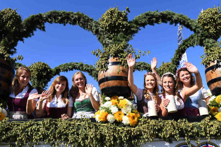 Auftakt zum Oktoberfest. Bedienungen winken beim Einzug der Festwirte auf einem geschmückten Wagen.