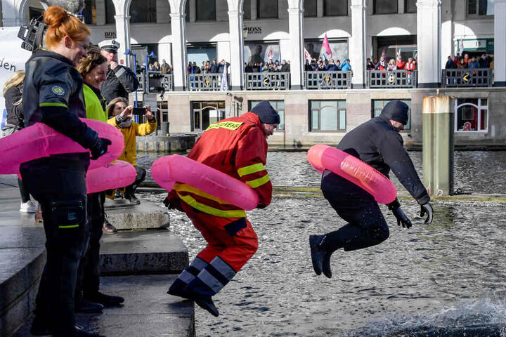 Mitarbeiter im öffentlichen Dienst springen mit Rettungsringen in die Binnenalster.