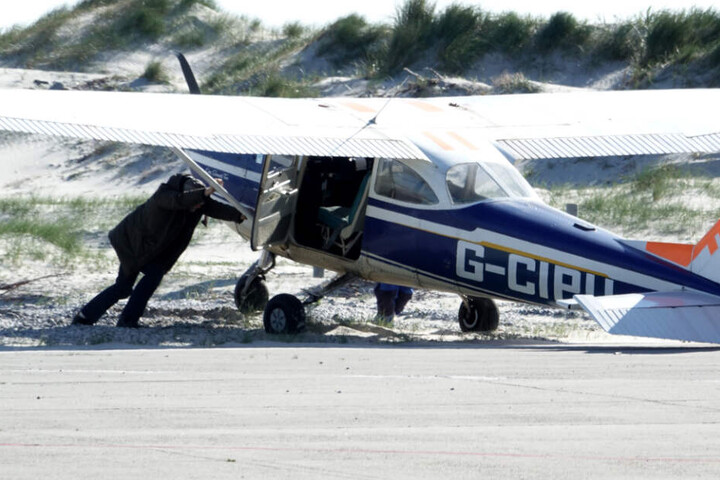 Die Besatzung schiebt das Flugzeug aus dem Sand zurück auf die Landebahn.