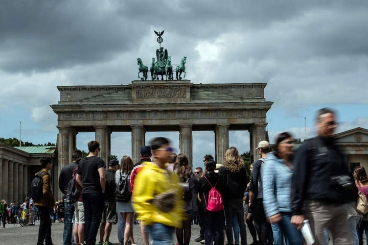 Dunkle Wolken ziehen über das Brandenburger Tor, während zahlreiche Menschen auf dem Pariser Platz stehen.