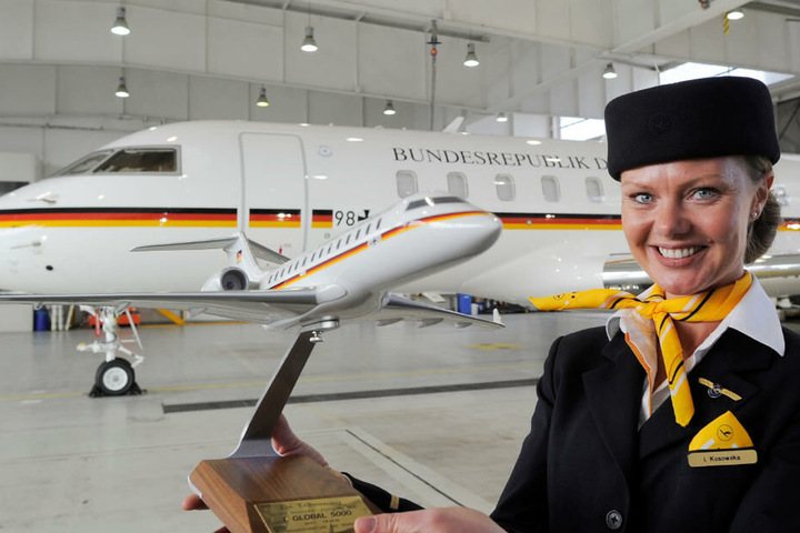 Flugbegleiterin Isabelle Kosowska zeigt in einem Hangar in Schönefeldvor einer Bombardier Global 5000 ein Modell des Fliegers.