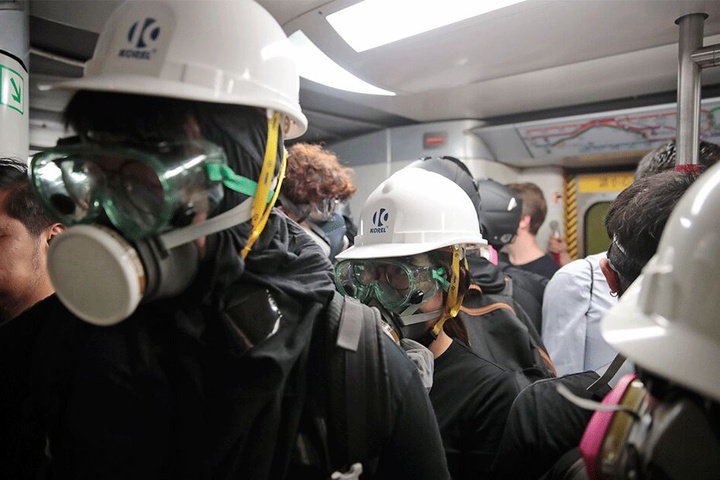 Mit Gasmasken und Helmen ausgestattete Demonstranten fahren im Zug nach Causeway Bay.