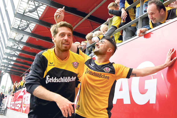 Andreas „Lumpi“ Lambertz (l.) hat ein Grinsen im Gesicht, während Aias Aosman Selfies mit den Dynamo-Fans schießt.