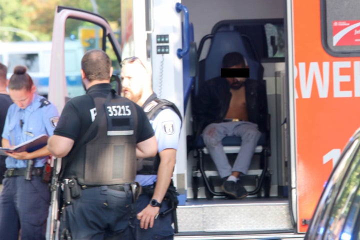Einer der festgenommenen Männer scheint eine Verletzung am Kopf zu haben. Seine Hände sind gefesselt und in Tüten gepackt.