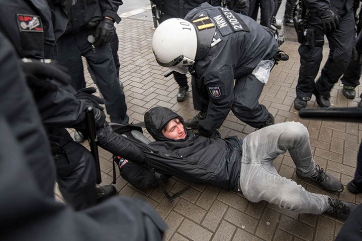 Ein Demonstrant wird von Polizisten davon getragen,