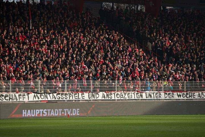 Ein Banner hängt am Zaun der Gegentribüne in der Alten Försterei mit dem Schriftzug: "Schafft Montagsspiele und Anstosszeiten unter der Woche ab!"