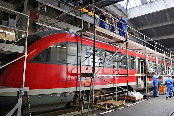Monteure verpassen einer Erzgebirgsbahn Zusatzaggregate auf das Dach eines Triebwagens.