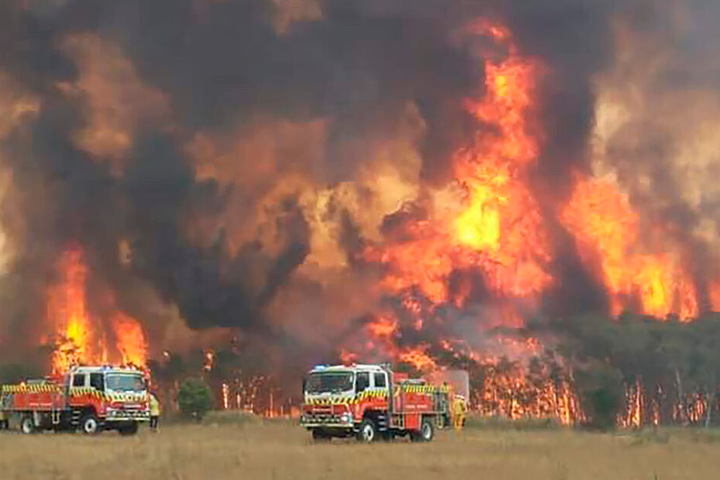 Dieses von der Feuerwehrbehörde des Bundesstaats New South Wales auf Twitter geteilte Foto zeigt Feuerwehrleute bei dem Versuch, Wohnhäuser um Charmhaven vor den Bränden zu schützen.