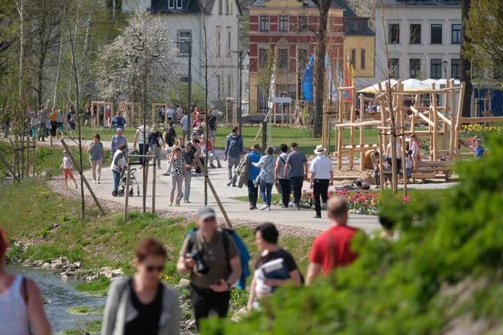 Besucher der sächsischen Landesgartenschau gehen über das Ausstellungsgelände am Mühlbach.