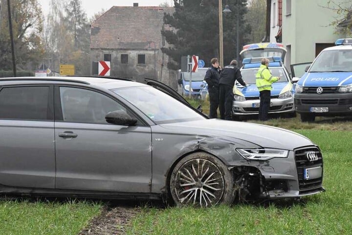 Der Audi steht auf der Wiese, im Hintergrund die Polizeifahrzeuge.