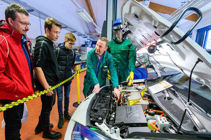Ausbilder Uwe Stürzbecher mit Besuchern in der KFZ-Werkstatt.