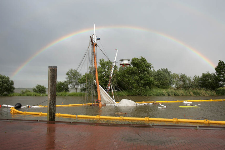 Dramatischer Untergang: Das gesunkene historische Segelschiff liegt fast gänzlich unter Wasser, während sich im Hintergrund ein Regenbogen aufspannt.