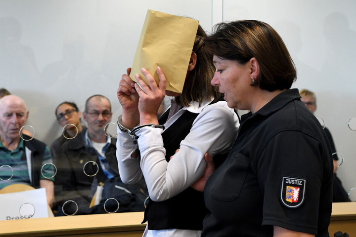 Mit verdecktem Gesicht wird die Angeklagte zum Auftakt eines Mordprozesses in den Gerichtssaal geführt.