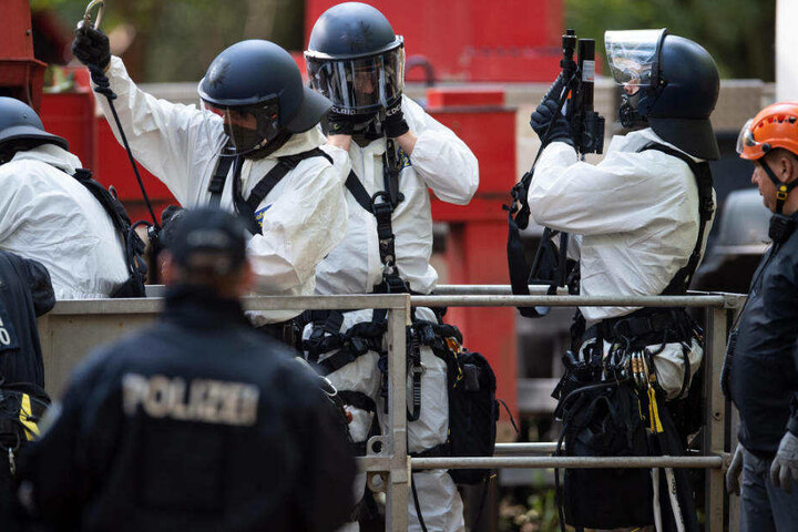 Polizisten tragen Schutzanzüge gegen den Bewurf mit Fäkalien.