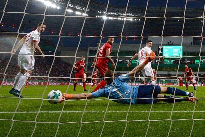 Leverkusens Torwart Bernd Leno (M) streckt sich vergeblich nach dem Ball von Münchens Robert Lewandowski (r), der das 0:2 erzielt.
