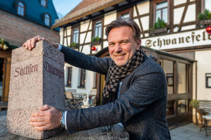 Zwei Bundesländer, ein Hotel: Hotelchef Andreas Barth (55) am Grenzstein von Thüringen und Sachsen.
