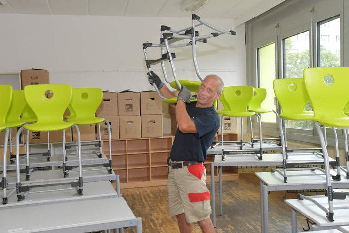 Während die Schüler ihre Sommerferien genießen, schleppt Umzugsmitarbeiter Ralf Erben (57) Bänke und Stühle.