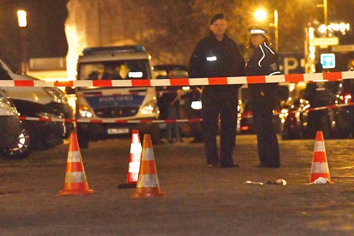 Polizisten stehen an der Stelle, wo zwei Männer angeschossen wurden.