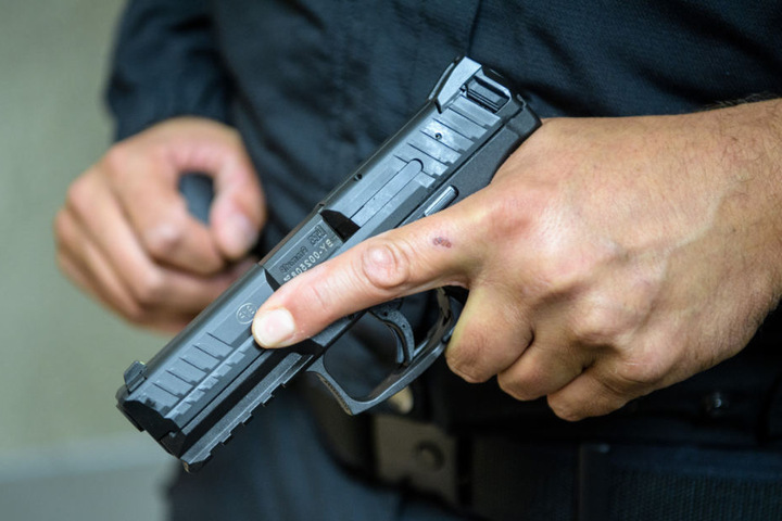 Ein Polizist hält eine Dienstwaffe in der Hand.
