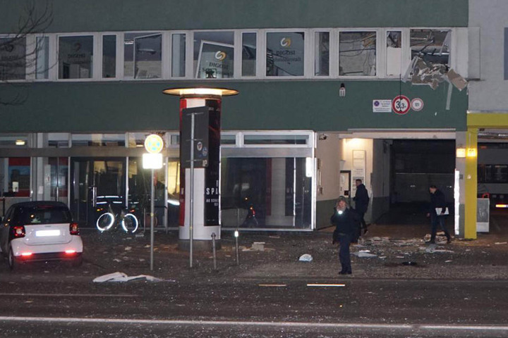 Die Trümmer liegen weit verstreut auf Gehweg und Straße. An den Fenstern (oben rechts) ist die Verwüstung zu sehen.