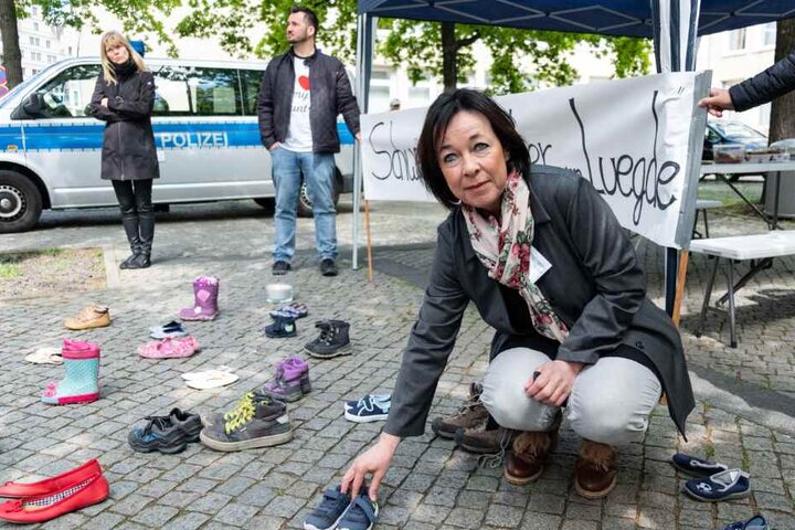 Sprecherin der Initiative "Kinder von Lügde", Ina Tolksdorf, verteilt vor dem Landtag in Hannover Kinderschuhe.