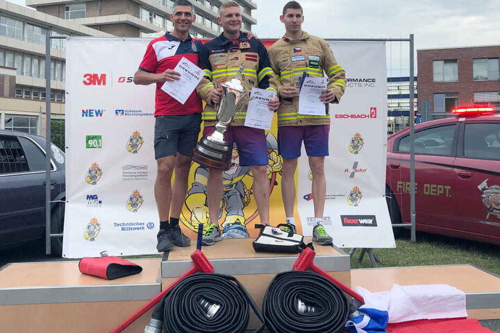 Michael Brousil (M) aus Tschechien freut sich über den Titel "härtester Feuerwehrmann", gefolgt von Marcin Zdzieblo (l) aus Polen und Pavel Kourik (r) aus Tschechien.