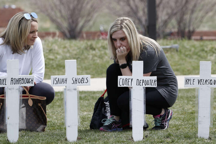 Cassandra Sandusky (r), Absolventin der Columbine High School, und ihre Freundin Jennifer Dunmore knien neben Kreuzen mit den Namen der Opfer des Attentats an der Columbine High School.