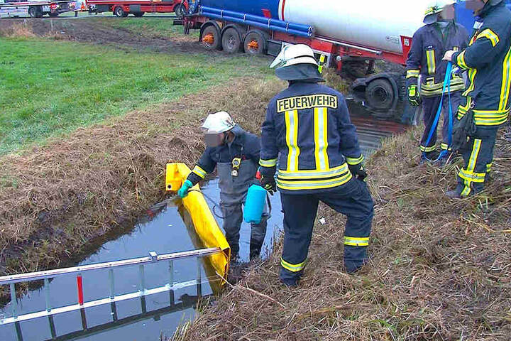 Die Kameraden der Feuerwehr legen den Wassergraben um den verunglückten Sattelzug trocken. Das Fahrzeug steckt tief im Boden fest.
