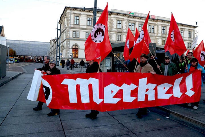 Teilnehmer einer von der "Merkeljugend" angemeldeten rechten Kundgebung mit einem Merkel-Transparent.