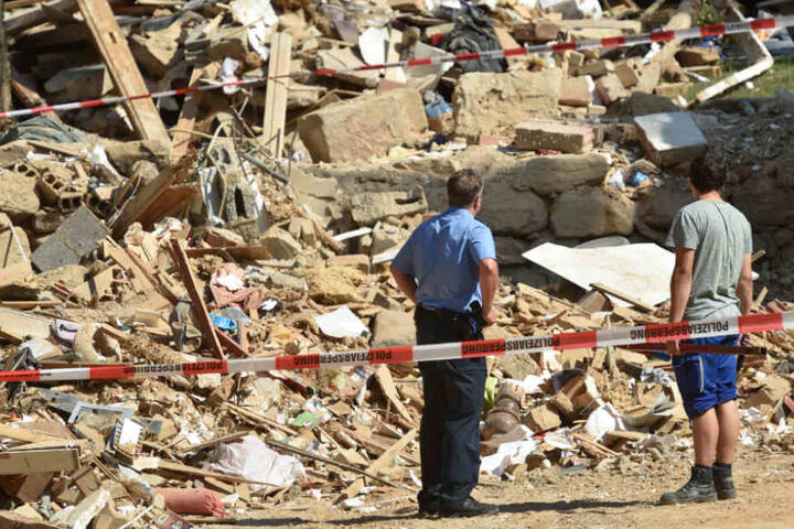Zwei Männer stehen vor der Ruine des Hauses.