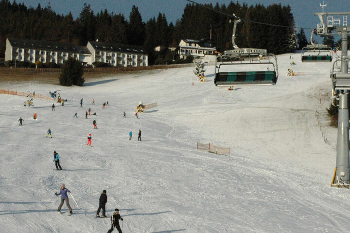 Skifahrer gleiten neben einem Sessellift einen Hang im Skigebiet Willingen hinunter.