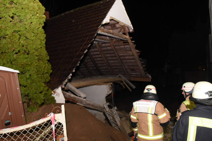 Feuerwehrmänner betrachten die eingestürzte Doppelhaushälfte.