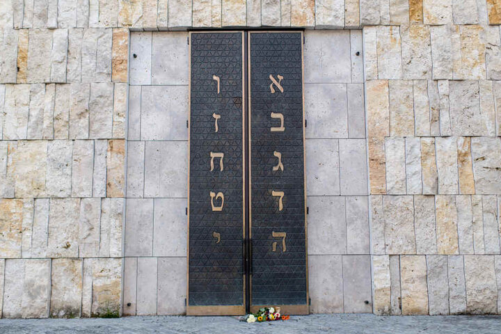 Menschen haben Blumen vor dem Eingangsportal der Münchner Hauptsynagoge Ohel Jakob abgelegt.