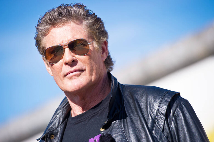 David Hasselhoff steht vor einem Rest der Berliner Mauer.