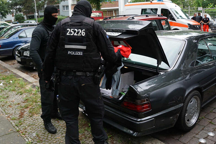 Fahnder durchsuchen den Kofferraum eines Mercedes der zu einem Tatverdächtigen gehört.