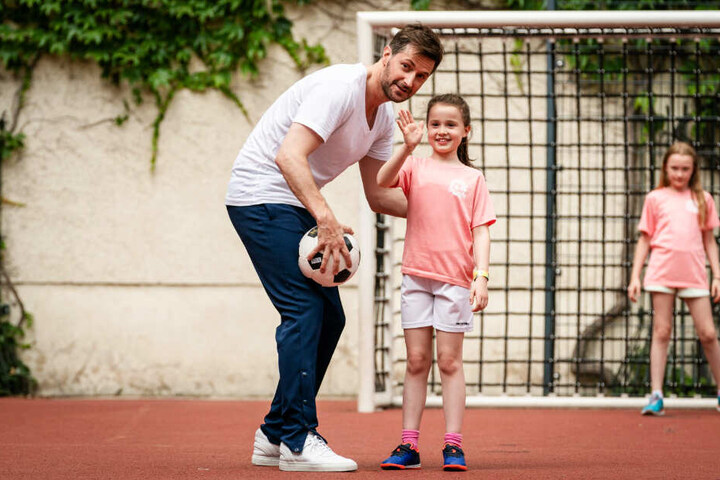 James Lewis (l., Richard Armitage) freut sich, dass Zoe (M., Sophia Ally) so gerne Fußball spielt.