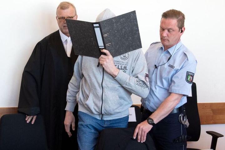 Der Hauptangeklagte Andreas V. versteckte sein Gesicht hinter einem Aktenordner, als er in den Gerichtssaal geführt wurde.