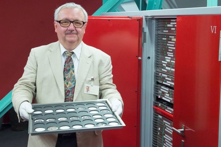 Rainer Grund, Direktor des Münzkabinetts, hält im Depot des Kabinetts in Dresden ein Tablett mit verschieden Münzen, die vorsorglich ins Depot verbracht wurden.