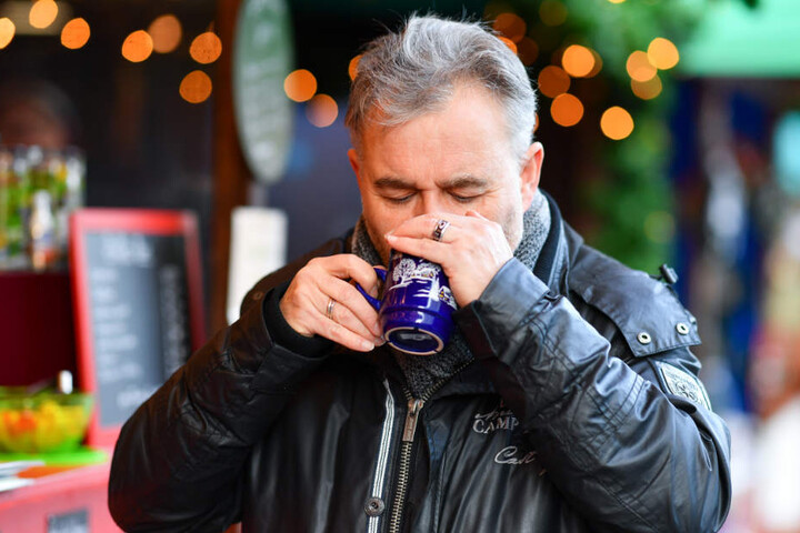 Lebensmittelkontrolleur Karl-Josef Leibig riecht auf dem Weihnachtsmarkt an einem Becher mit einer Glühweinprobe.