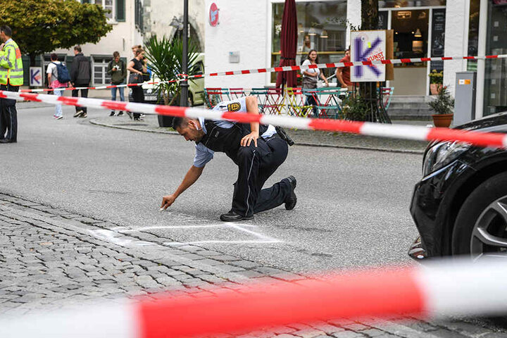 Ein Polizist markiert im abgesperrten Tatort auf dem Marienplatz einen Bereich. Nach Angaben der Polizei lag dort das Tatmesser.