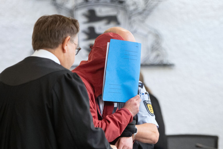 Der Angeklagte (M) in einem Mordprozess nach einem tödlichem Unfall wird von einem Justizbeamten in einen Gerichtssaal des Landgerichts Stuttgart geführt.
