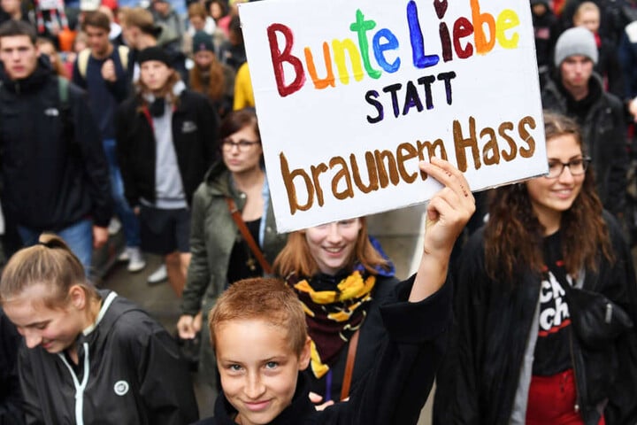Ein junger Teilnehmer des Demonstrationszuges hält ein Schild mit der Aufschrift "Bunte Liebe statt braunem Hass".