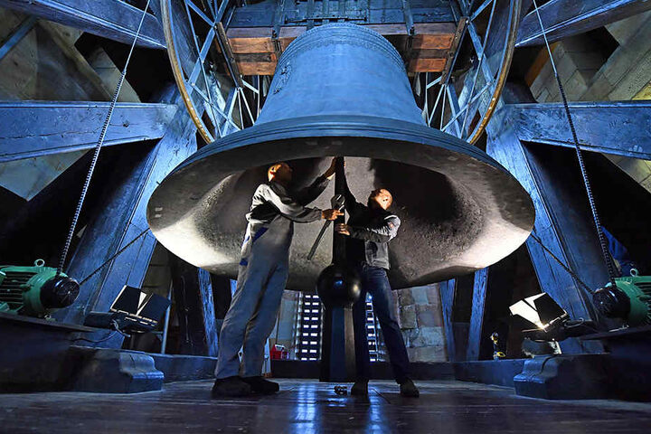 (v.l.) Glockenwart Uwe Kramer und Mechaniker Christian Garamvölgy arbeiten unter der meterhohen Glocke.
