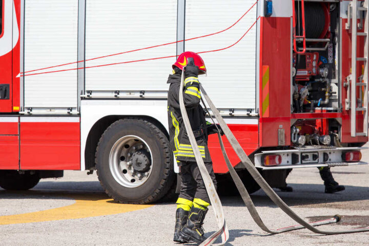 Ein Feuerwehrmitglied rollt nach dem Einsatz einen Schlauch auf. (Symbolbild)